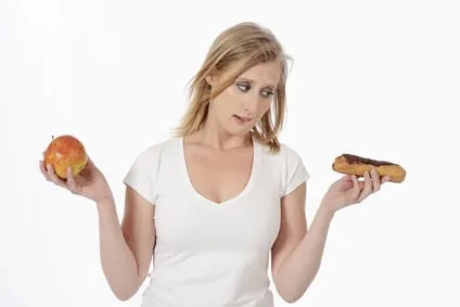 femme hésitant entre pomme et pâtisserie